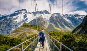 Amazing Nature of Hooker Valley Track in Mount Cook, New Zealand. Young Family walk on Suspension Bridge.
