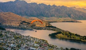 Paragliding over Queenstown and Lake Wakaitipu with The Remarkables in the background from viewpoint at Queenstown Skyline, New Zealand
